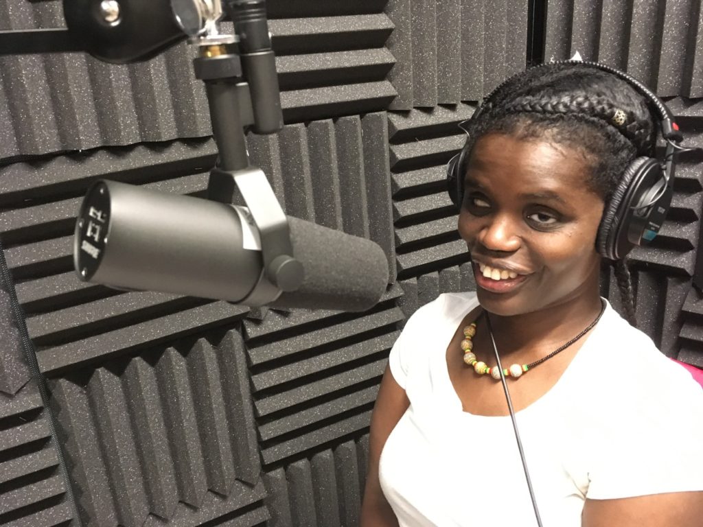 In this photo, Abby Griffith, is sitting in front of a microphone inside an audio sound-booth. She is being interviewed about her story.