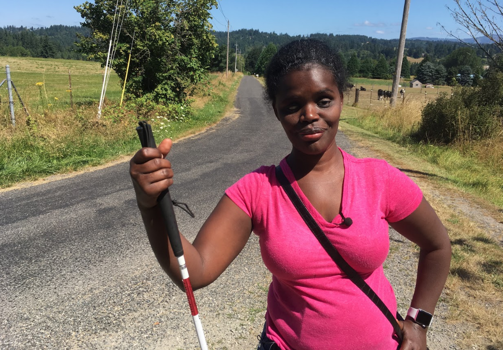 Abby stands, holding onto her cane, while posing at the end of her mother's driveway